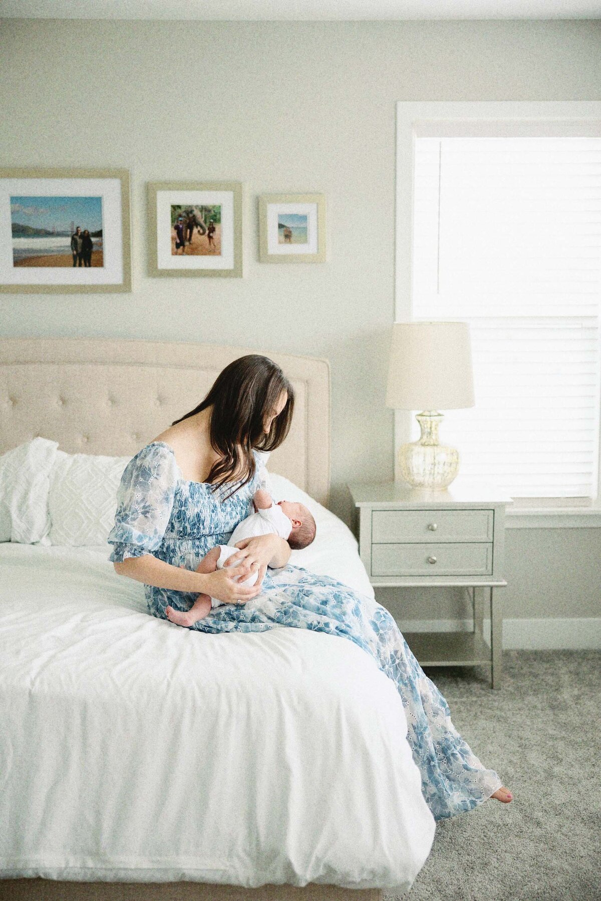 mom sitting on the bed holding baby