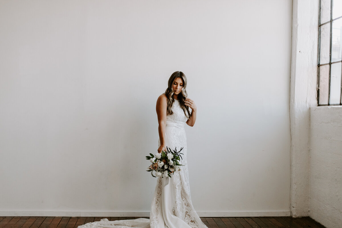 A bride holding a bouquet looking at the floor