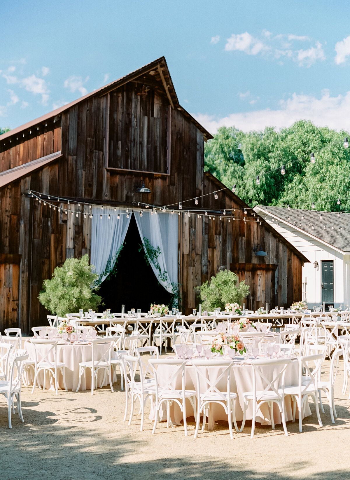 outdoor wedding reception against backdrop of rustic barn