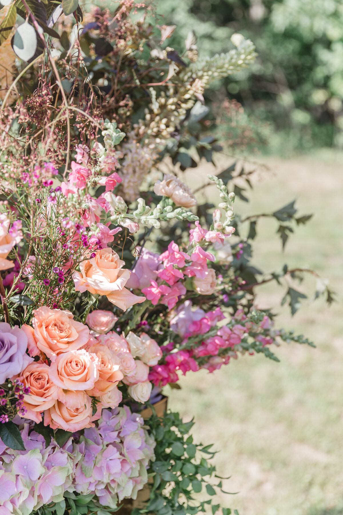 A close up of flowers on a  ceremony arch with pink, peach, and purple flowers