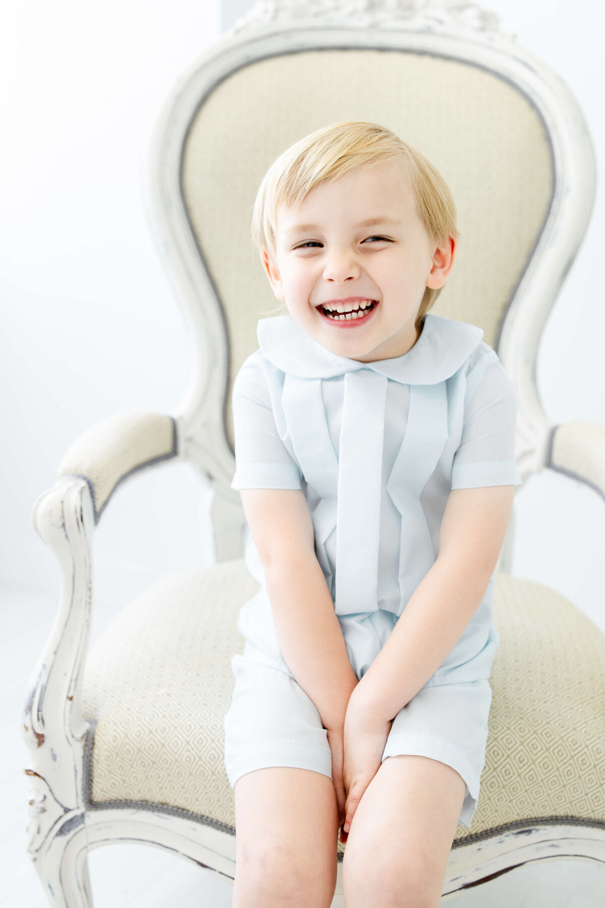 Child sitting in a chair with a blue heirloom outfit posing for heirloom photography