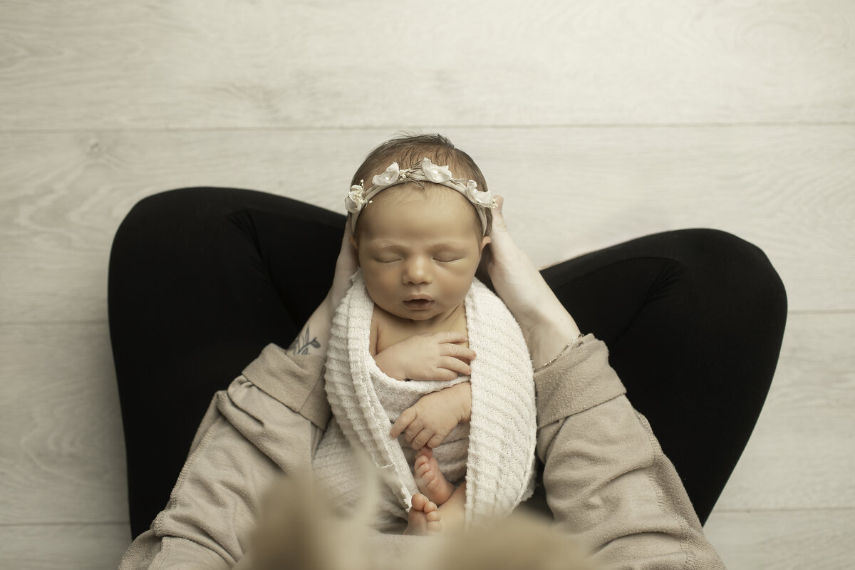 Mom lovingly cradling her newborn baby, wrapped snugly in her lap, sharing a tender and intimate moment of warmth and connection