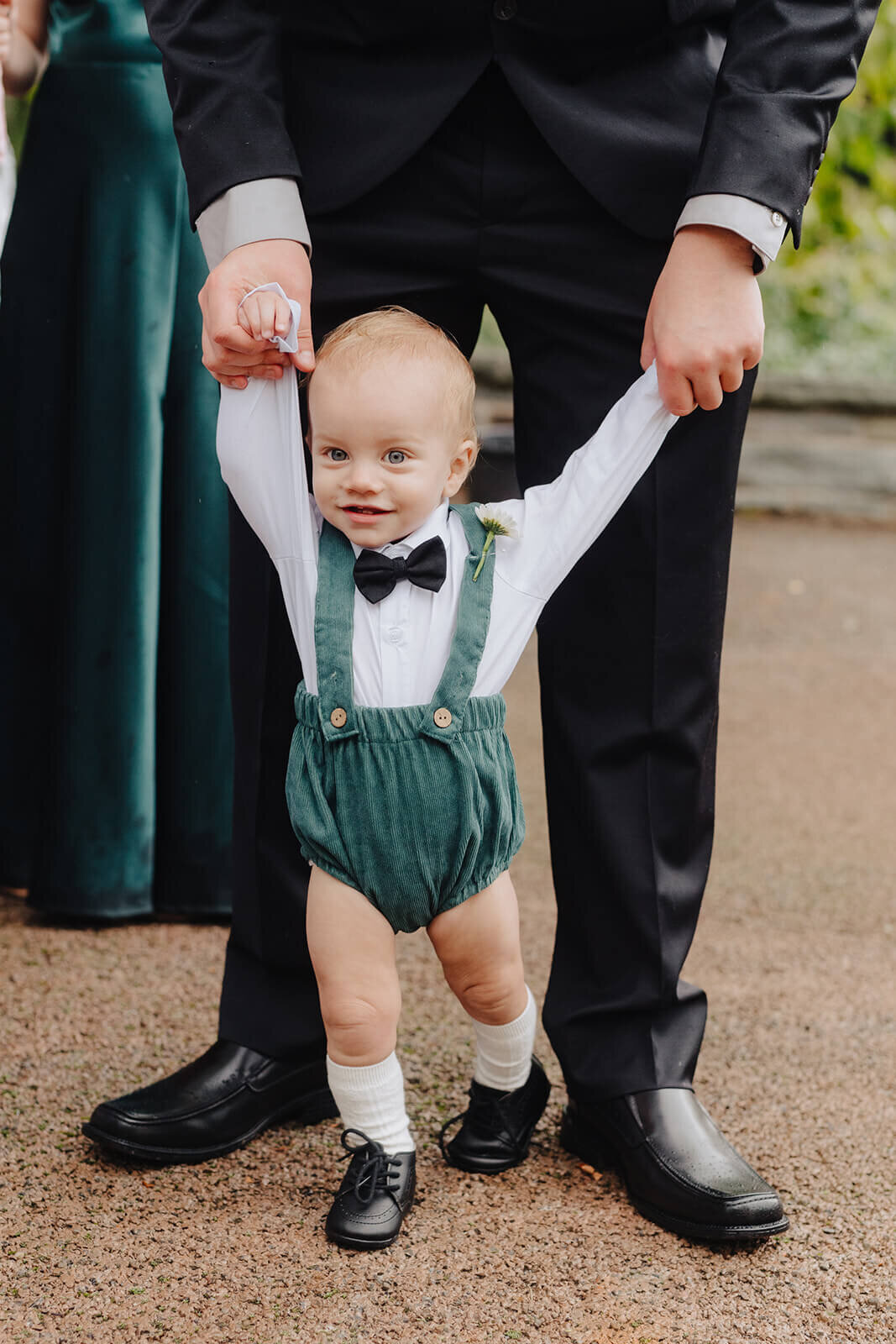 Baby wearing white shirt and bow tie and green onesie