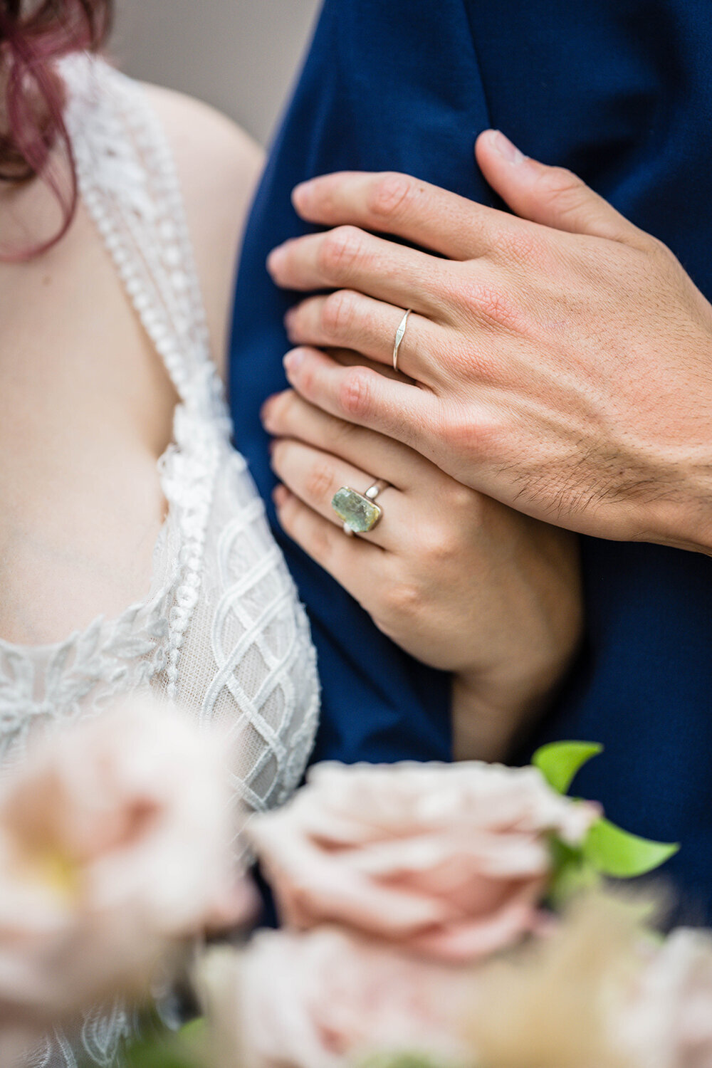 A close-up shot of a bride’s hand wrapping around her partner’s bicep as the groom places his hand gently on top of hers.