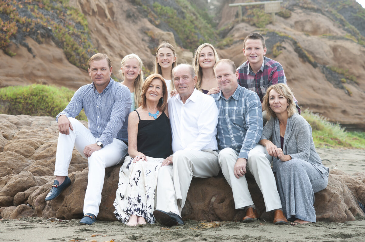 large family posing on the beach with large  mountain in background