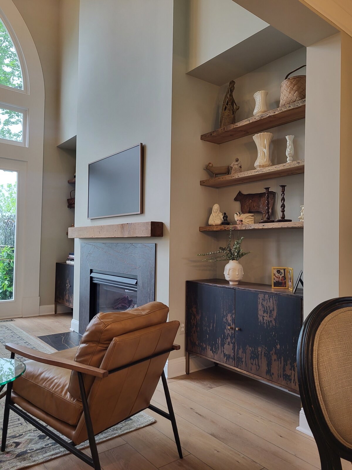 Fireplace with antique wood mantle and antique wood bookshelves in the nooks beside the fireplace with artisticaly painted black and tan cabinets