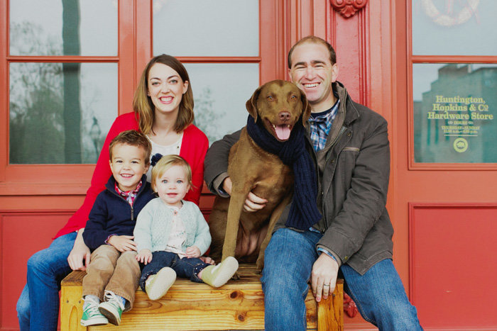 Parents two kids and a dog sit on a brown box smiling at the camera in Sacramento