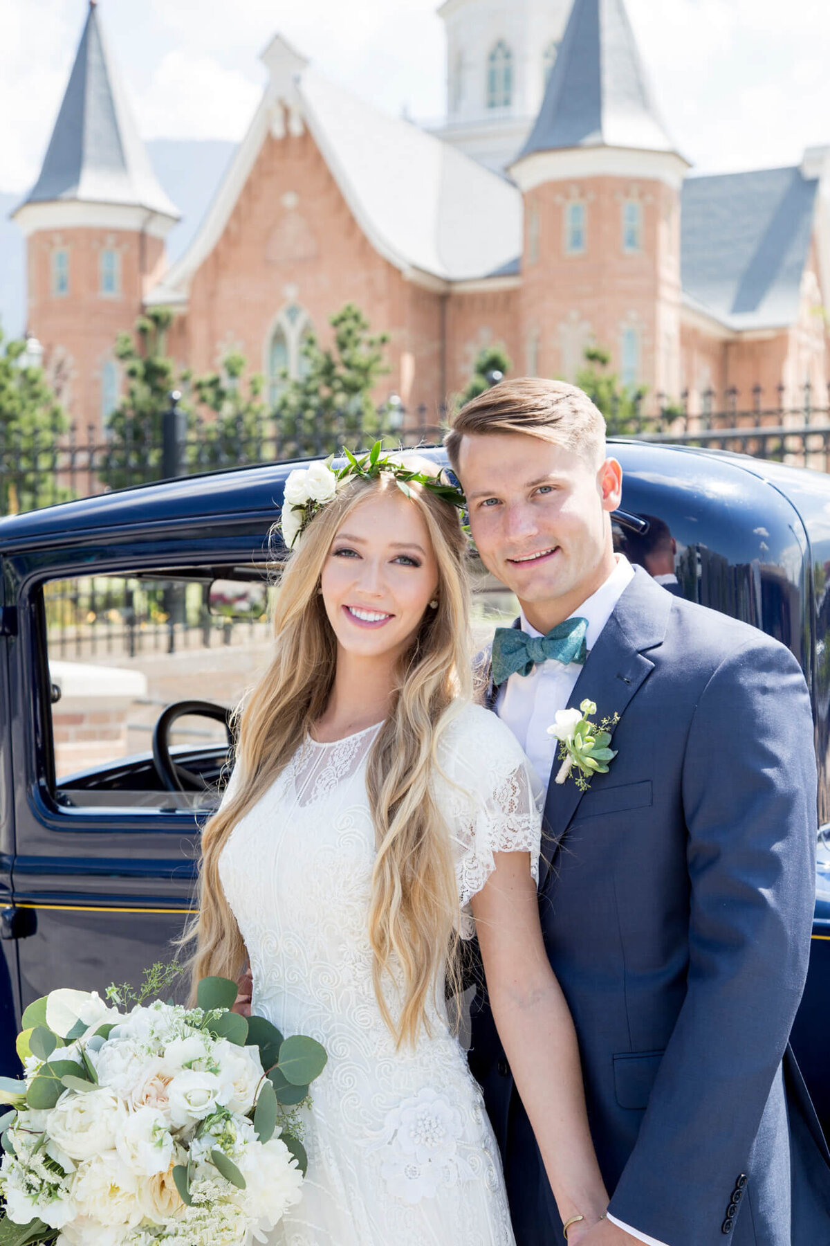 a bride and groom in front of a car