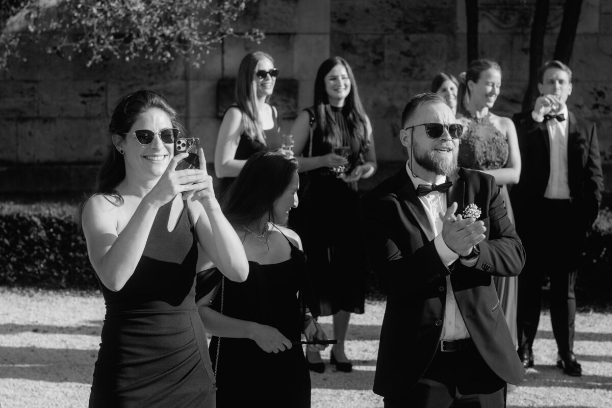 Black and white wedding moment photography of guests celebrating the wedding couple.