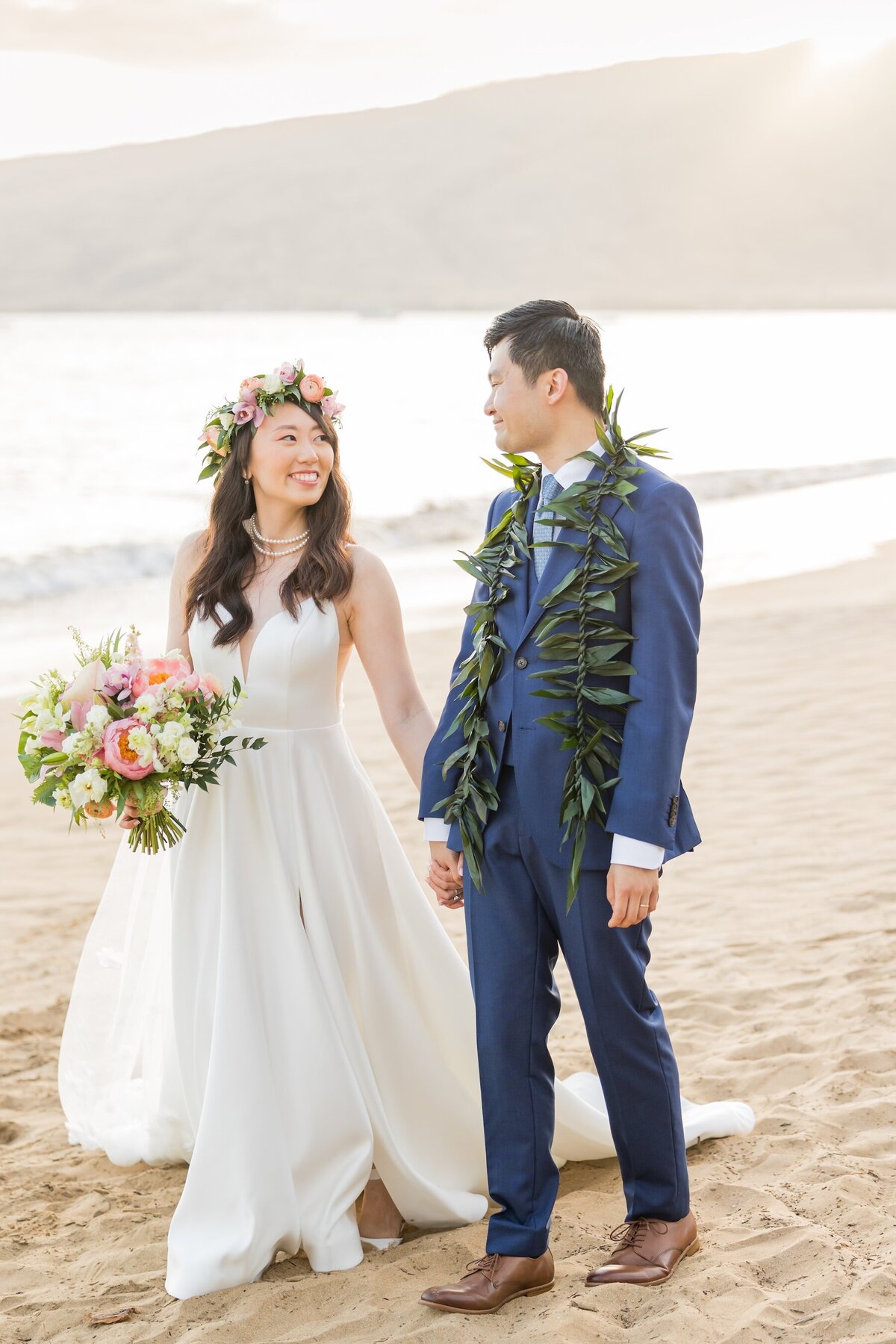 bride looking at groom holding hands walking in the sand in Maui, Hawaii