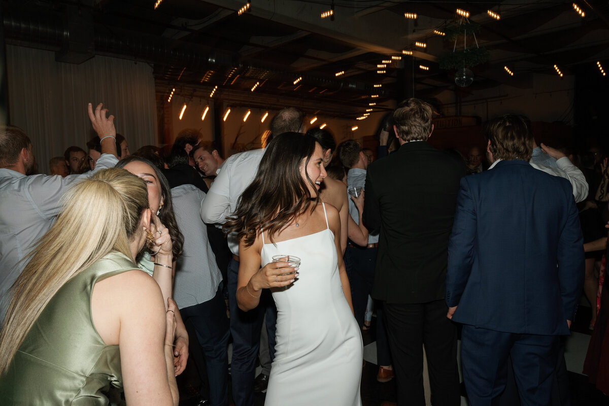 Bride holding a drink and dancing at wedding reception by Shelby Ann Photos