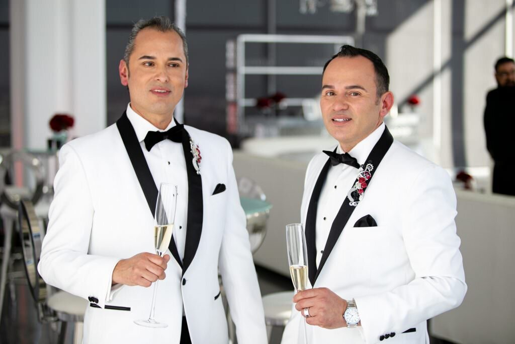 Two grooms smiling and holding glasses of champagne