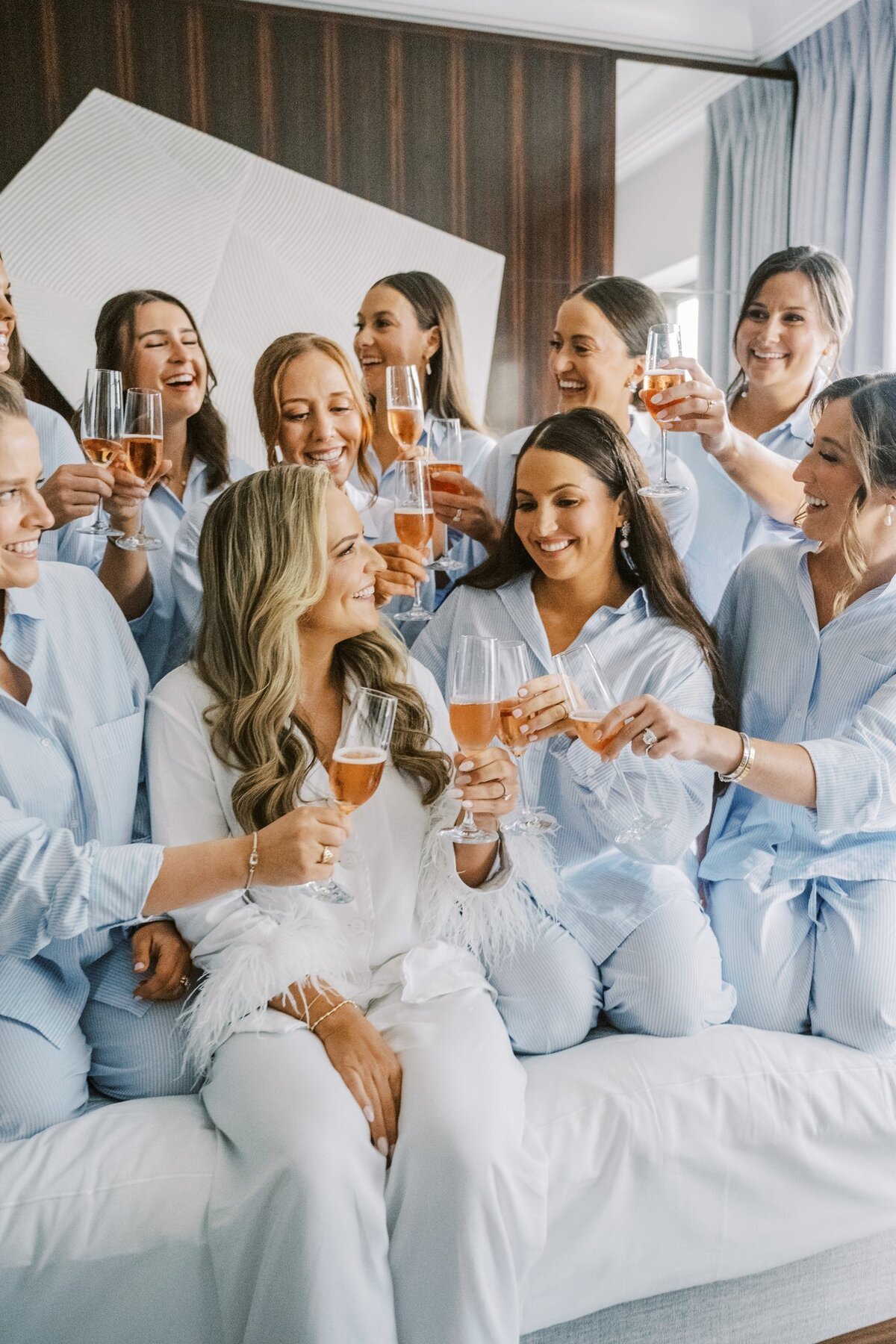 Bride cheers with bridesmaids while getting ready