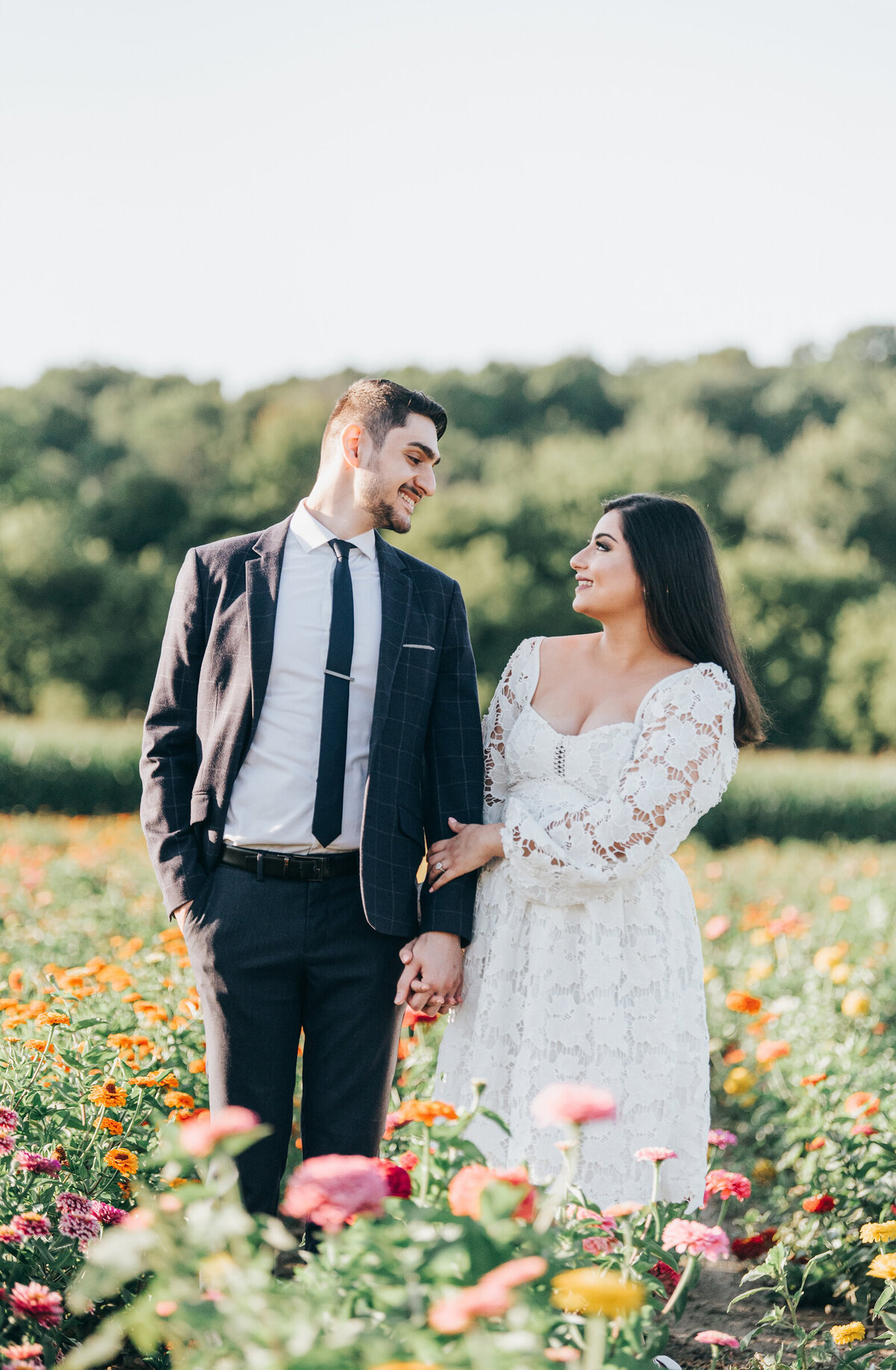 Couple posing for engagement photos in  a whimsical wildflower field during their Summer engagement session
