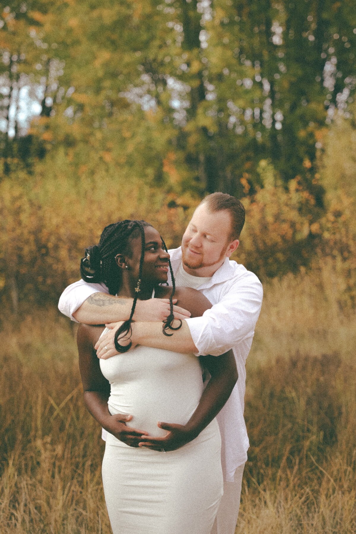 Romantic Maternity Session with Couple Embracing in Field at Sunset