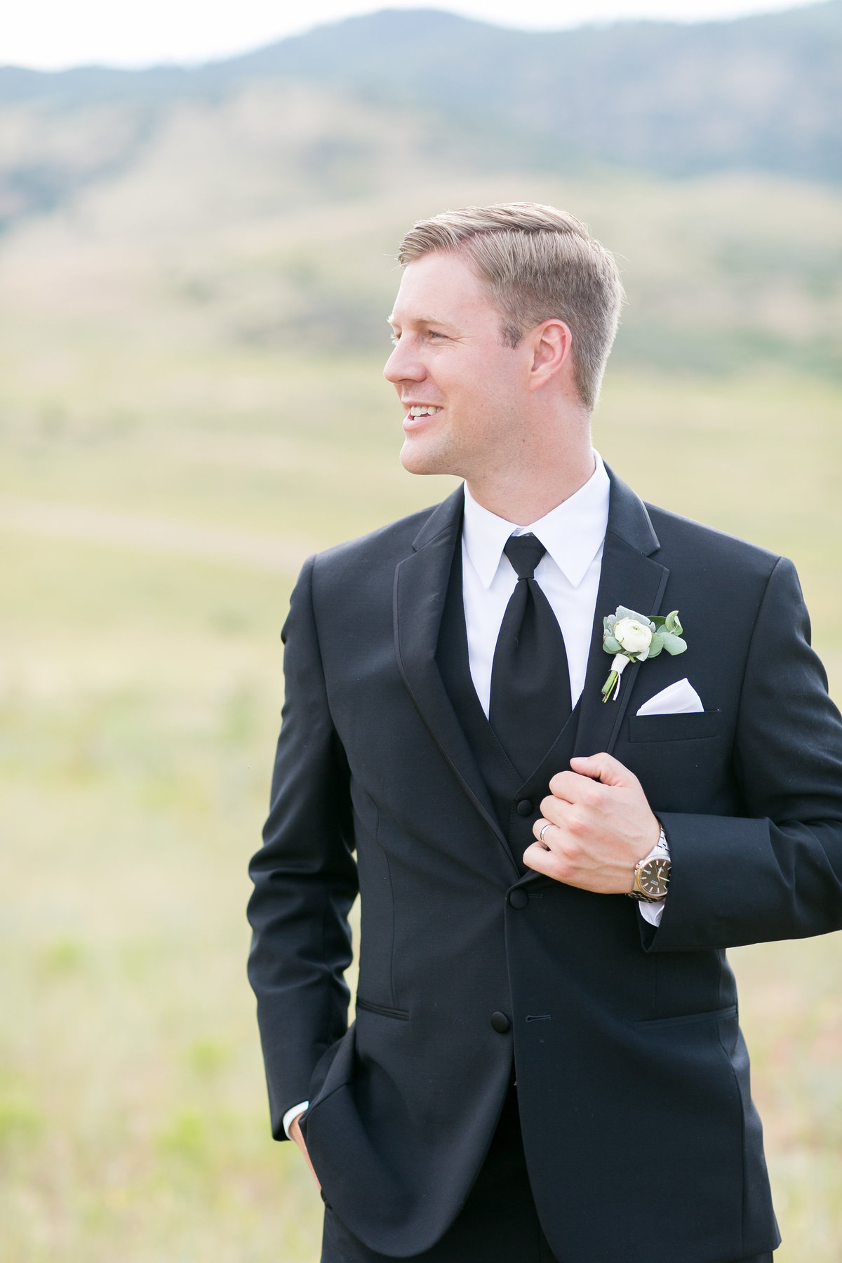 Groom standing in front of mountains