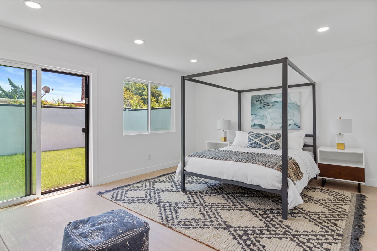 bright-primary-bedroom-sliding-glass-door-modern-four-poster-bed