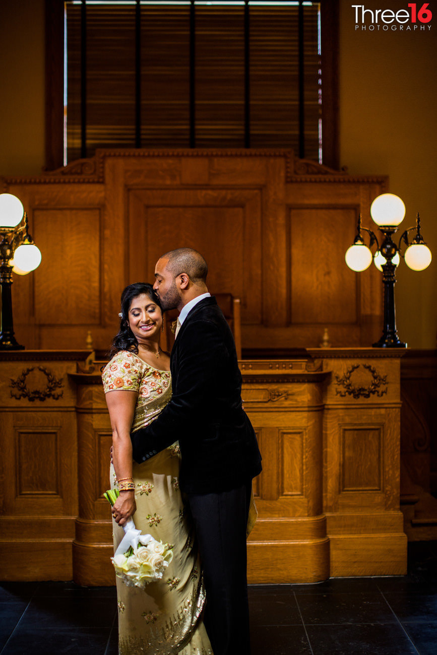 Groom kisses his Bride's head after they eloped at the courthouse