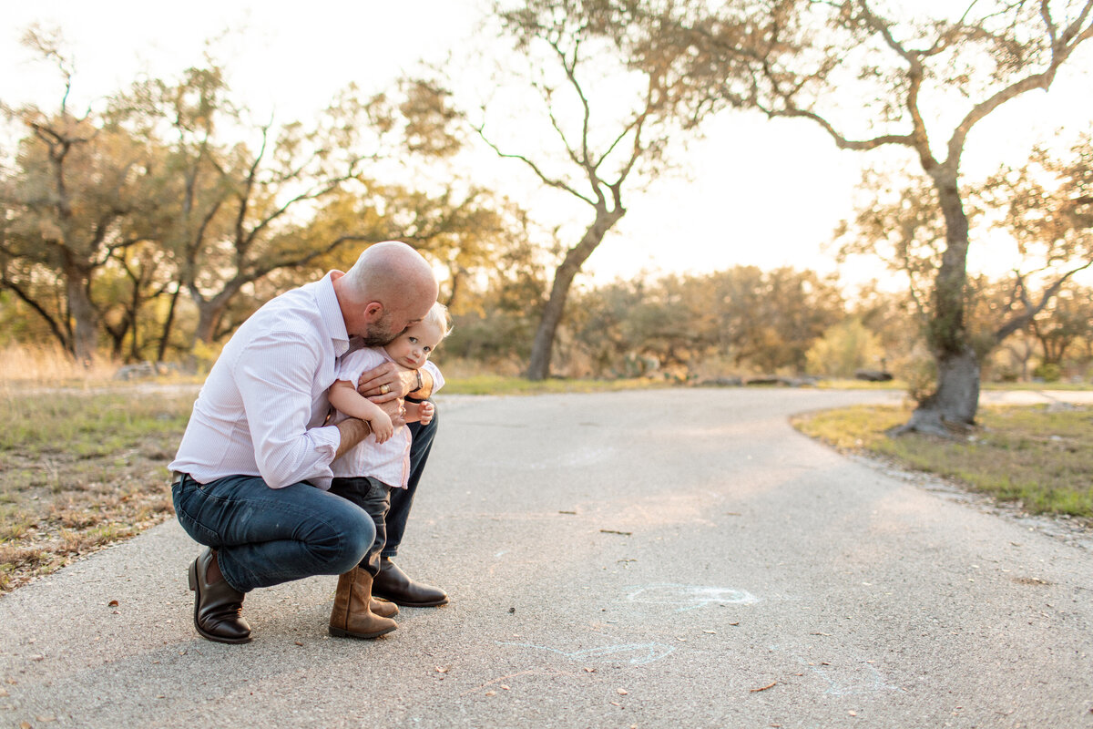 Candid moment of a dad and son together in their driveway, captured by Sara James, a San Antonio family photographer.
