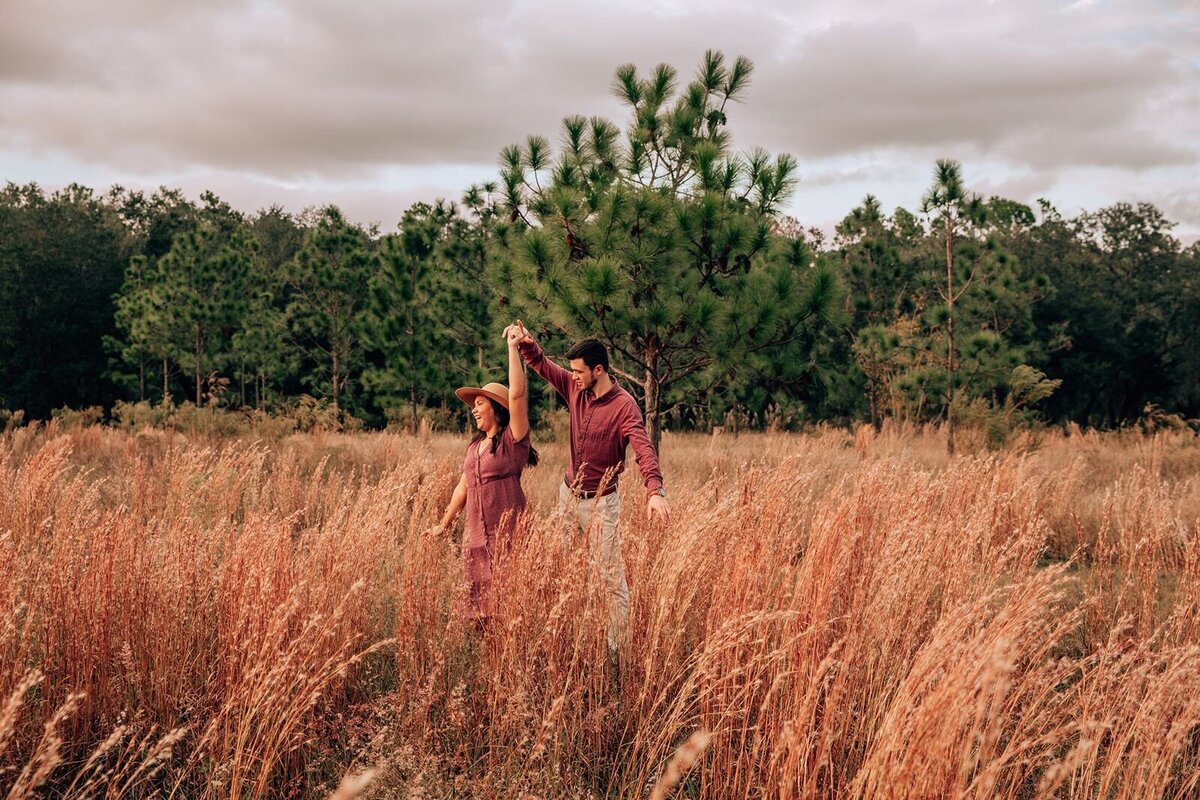 engaged couple twirling in a tall grass field at lake louisa state park