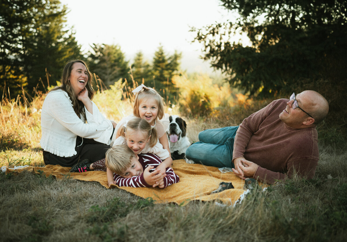 mother, chases daughter while dad watches holding baby during photography session with Portland family photographer