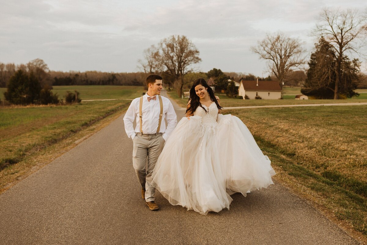 bride and groom run down a gravel path