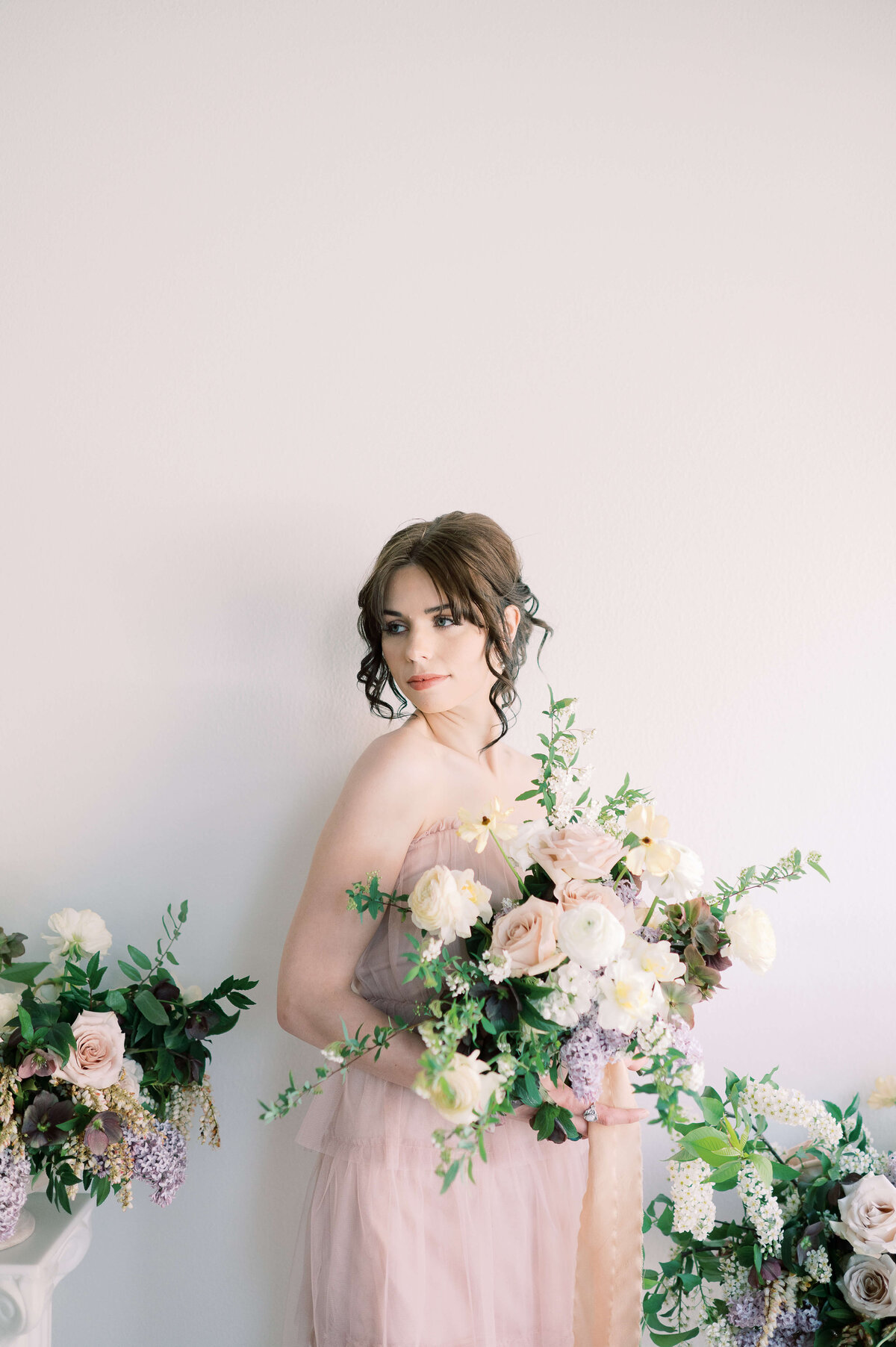 woman holding large bouquet of flowers in ivory, peach, pale pink, lavender and greenery