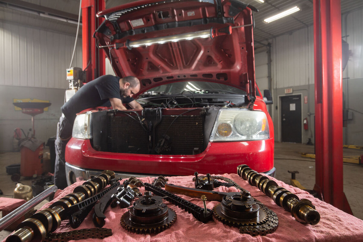 A man is working on the engine of a red car
