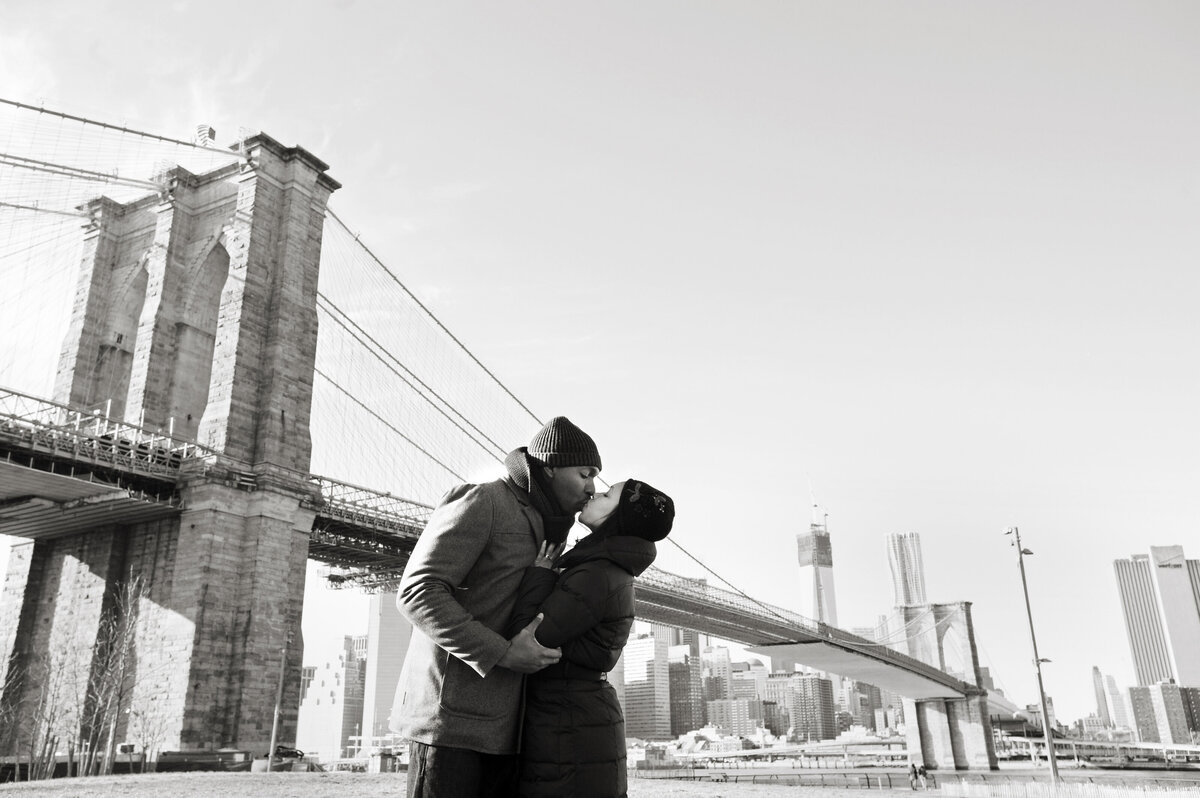 A couple kissing in front of the Brooklyn Bridge 