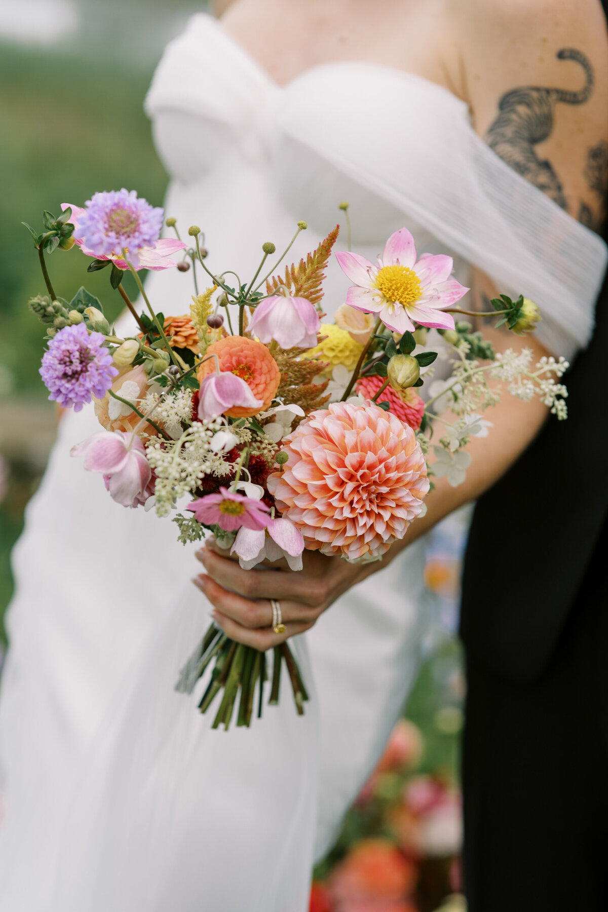 A bride in a strapless dress holds a bright, colourful bouquet at the Willow Inn.