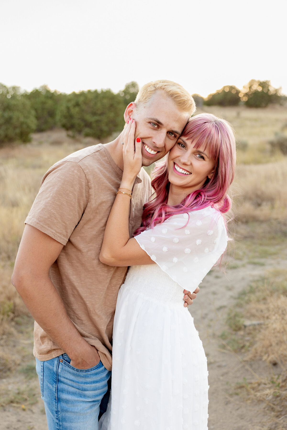 The lady grabs her husbands face and pulls him in close for a smiley portrait
