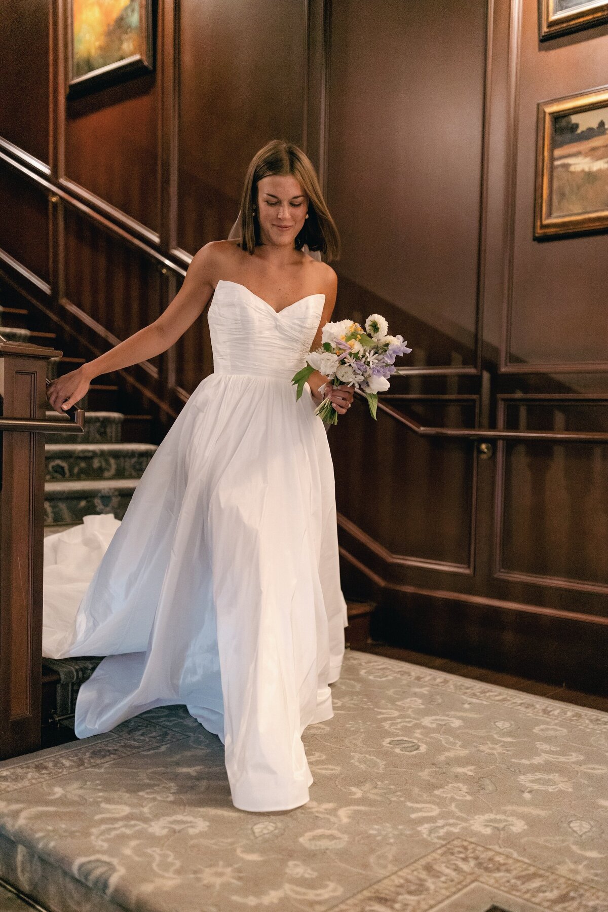 aa bride walking down steps while carrying a bouquet