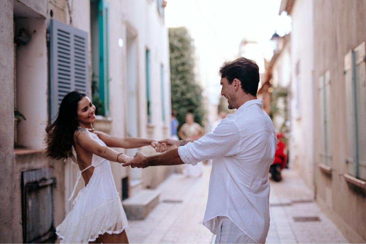 Couple with their arms out holding hands as the swing around dancing in the street in Saint Tropez, France.