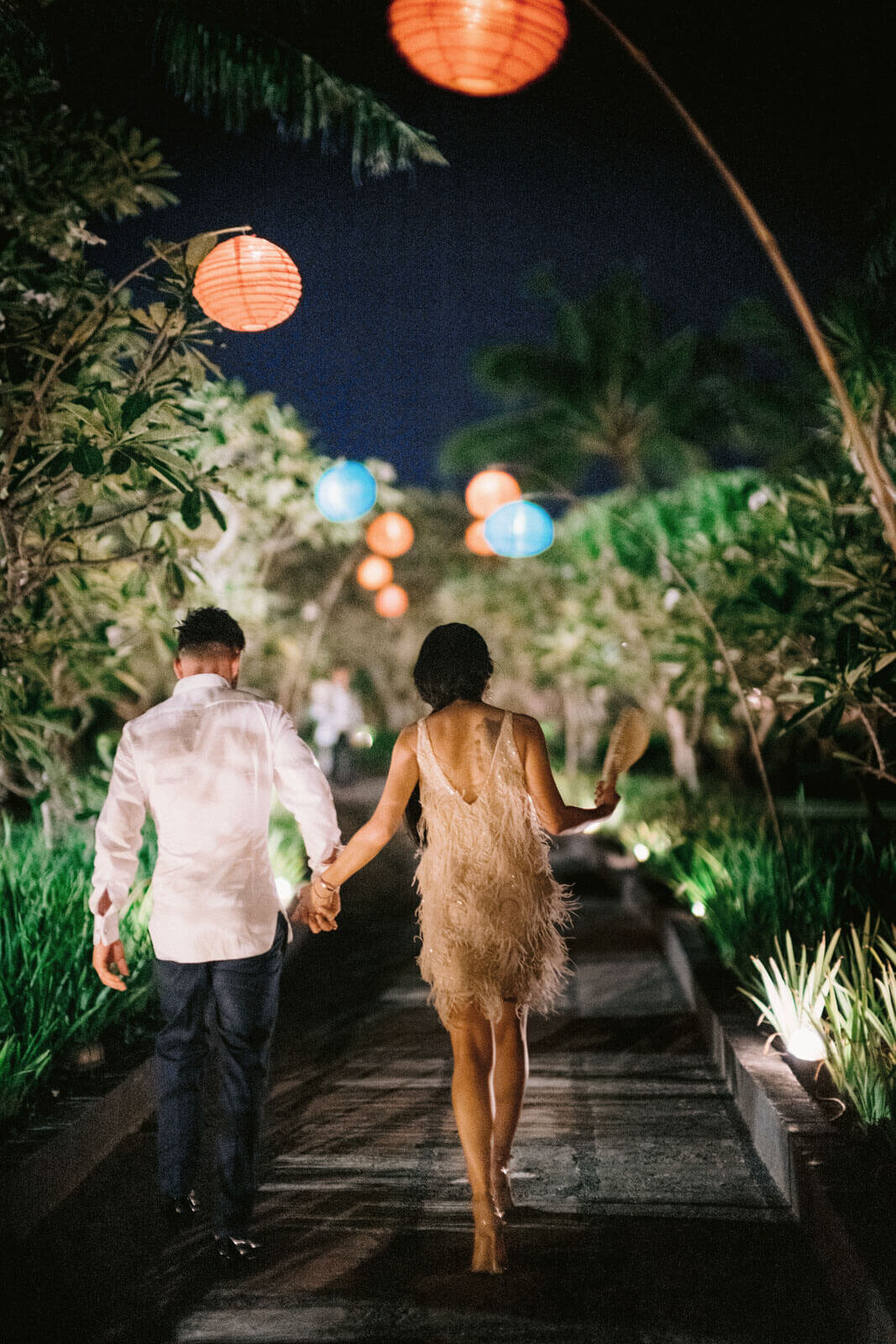 The bride and groom are walking away in a garden path, after the party in Khayangan Estate, Bali, Indonesia. Image by Jenny Fu Studio