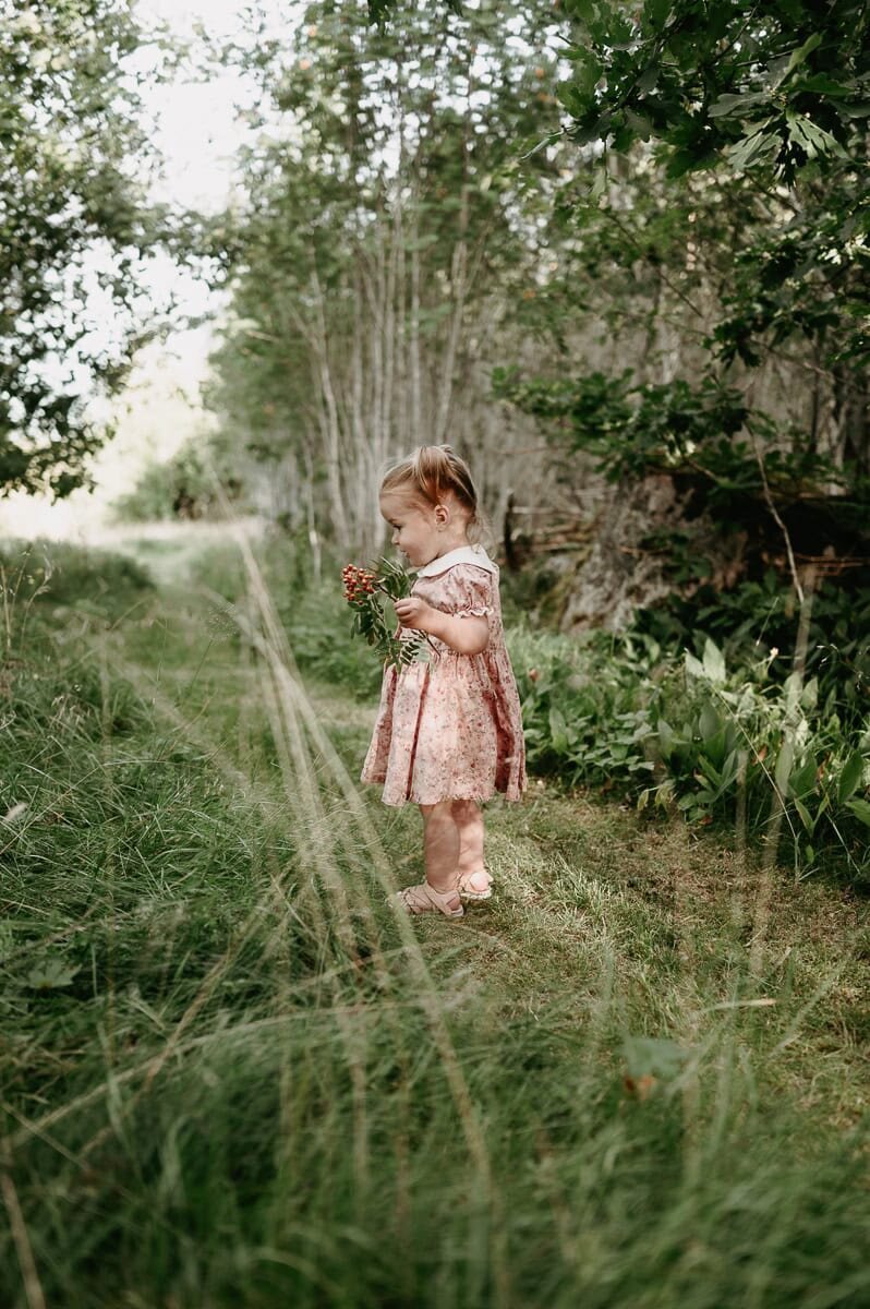Tjej står på en stig i rosa blommig klänning.