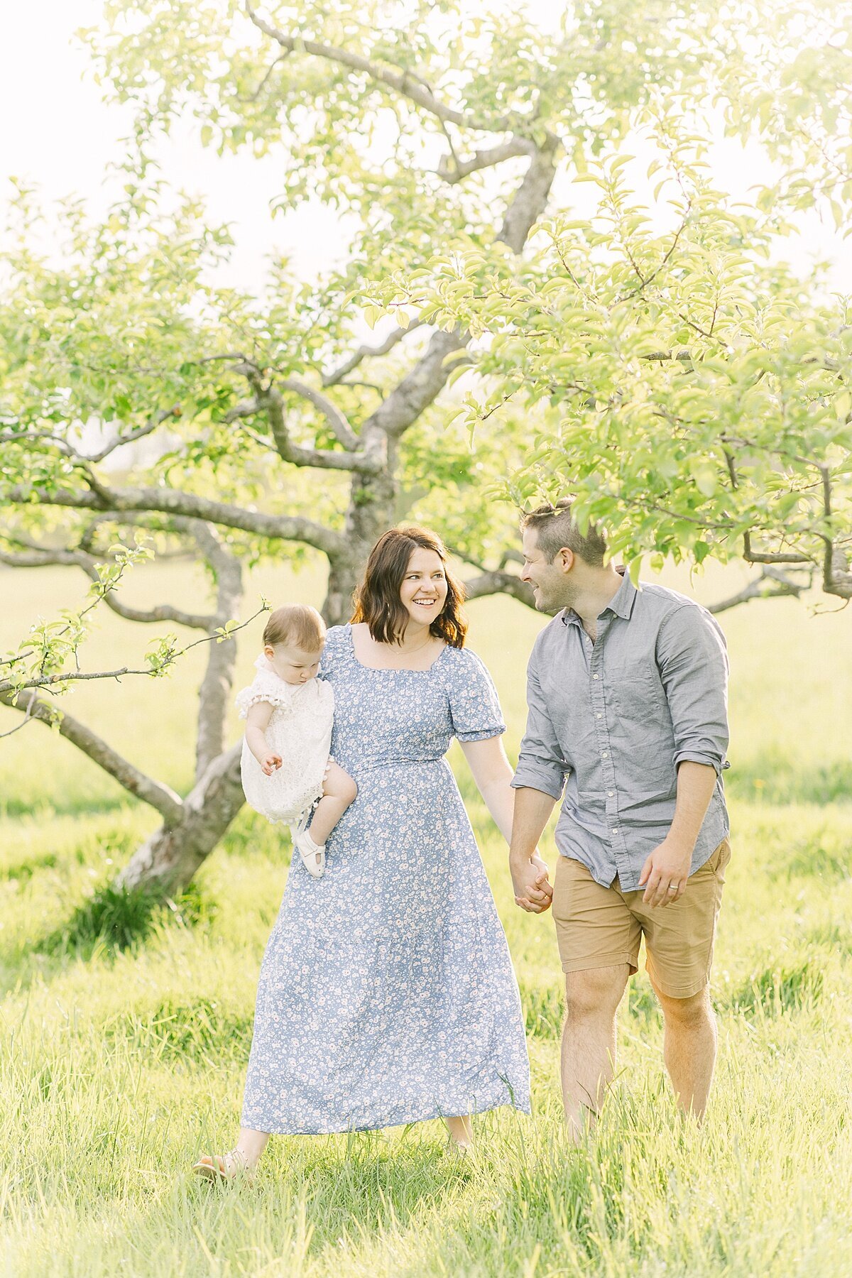 family walks through orchard duirng spring family photo session with Sara Sniderman Photography in Natick Massachusetts