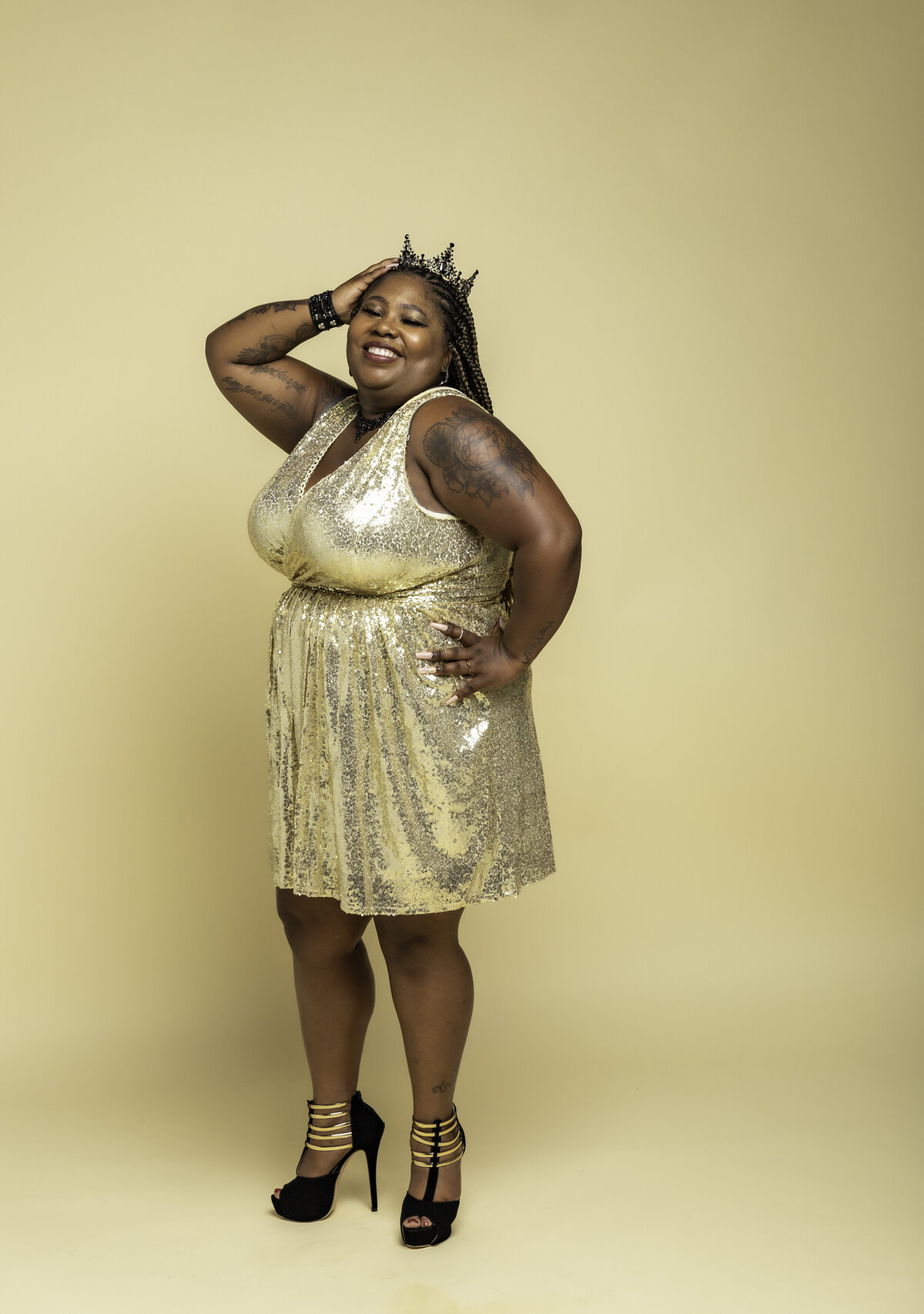 Plus size Black woman in a gold dress, black heels, and black crown