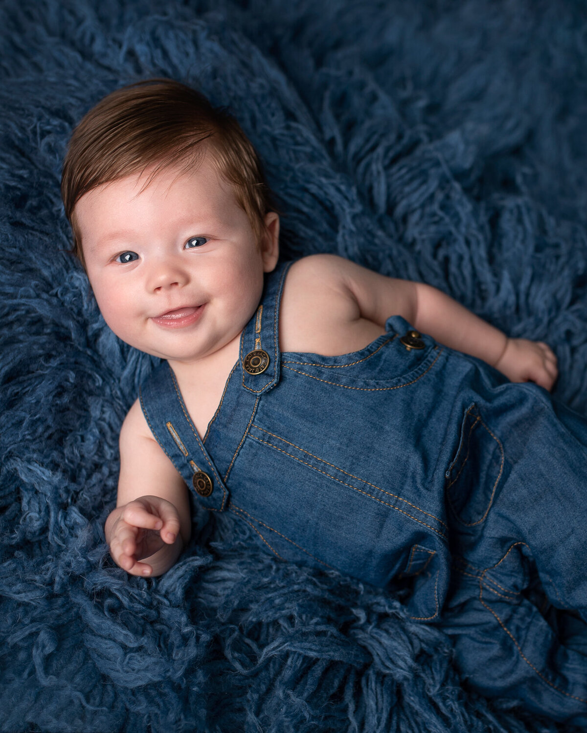 Adorable little baby in jeans and blue furry background by Laura King Photography