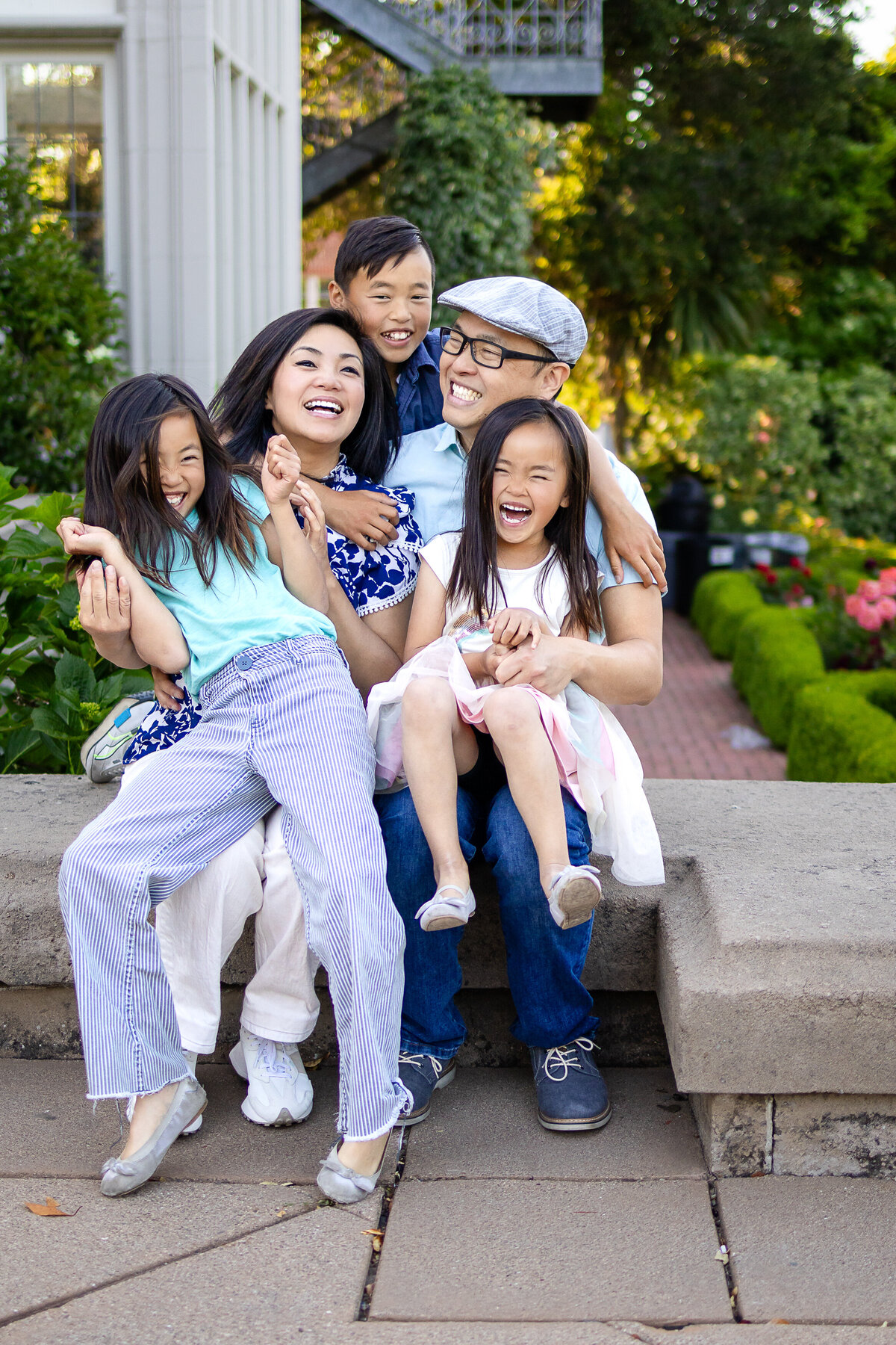 Golden hour portrait of a family of five seated on the grass beneath a glowing tree – joyful, natural light family photography by Ellobelle Photography in the San Francisco Peninsula kohl mansion Burlingame