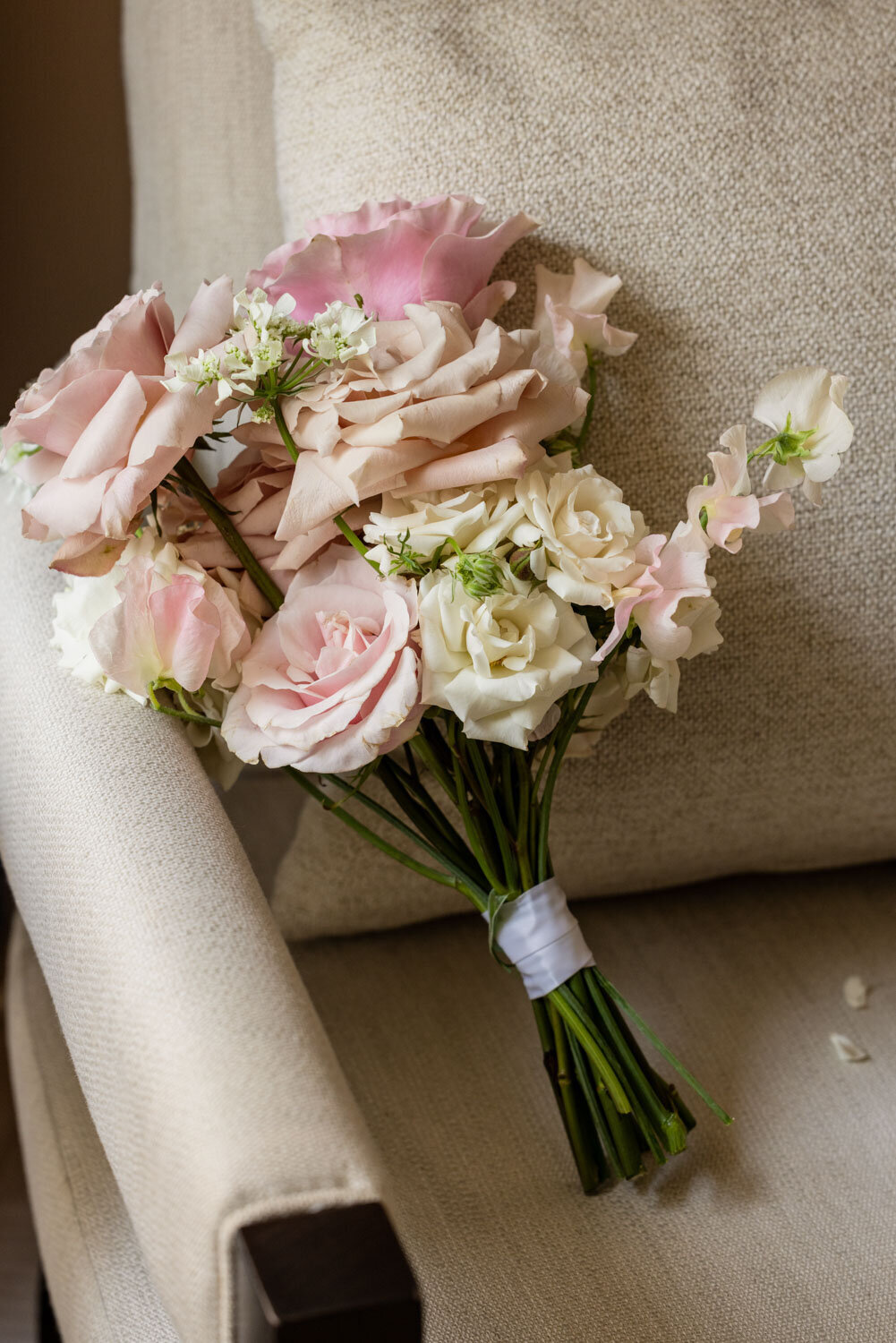 A bouquet of pink and white roses sits on a chair