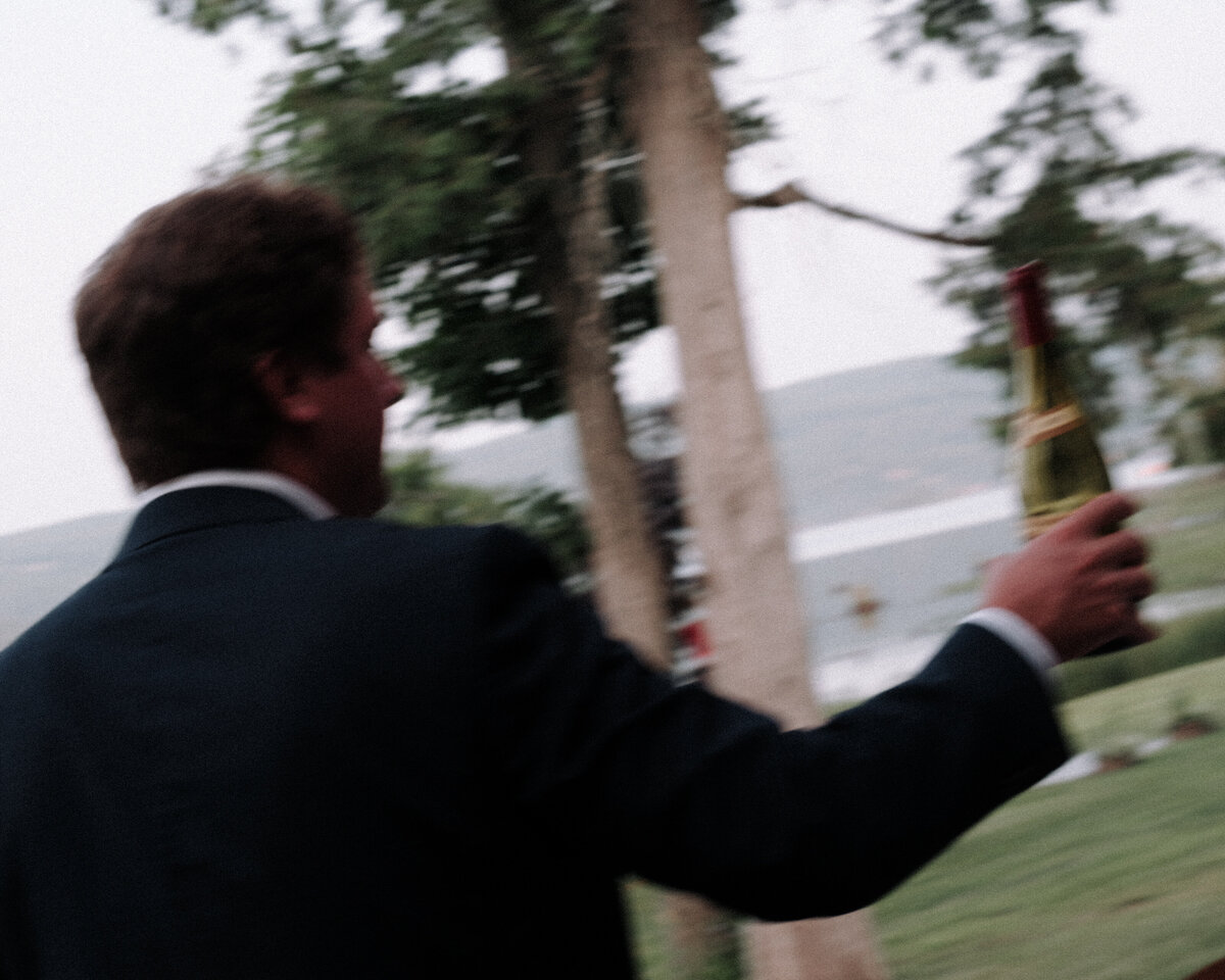 groomsman carrying wine over to the table at the cottage