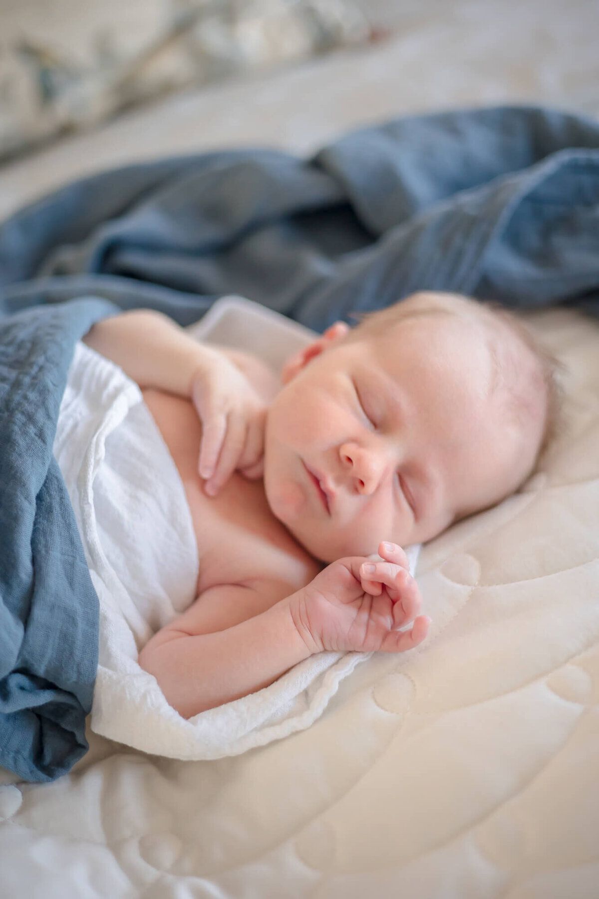 Las Vegas newborn baby boy sleeping on a bed wrapped in dusty blue swaddle