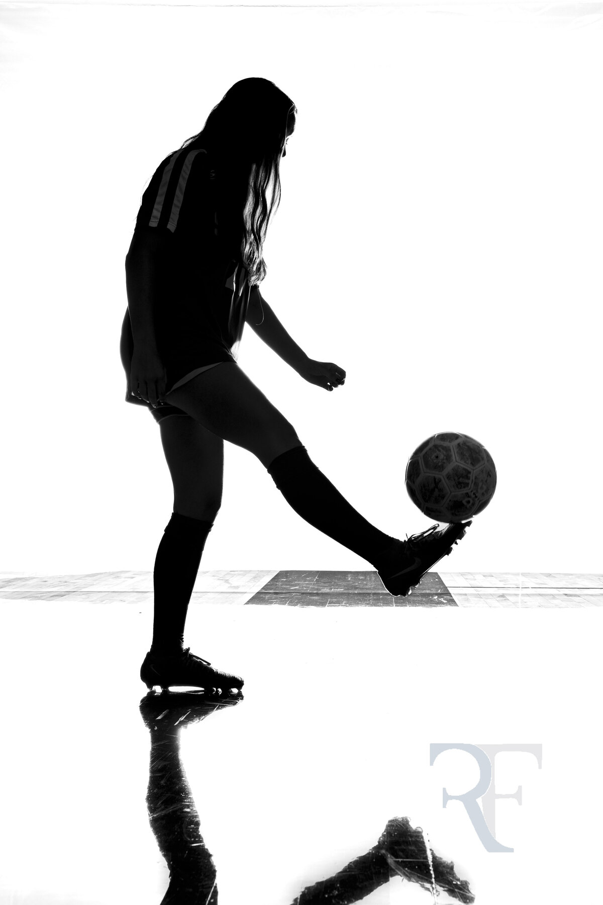 Photographer in Avon | Rob Faber Photography | Silhouette of a female soccer player juggling a ball mid-air, captured in dramatic backlighting.