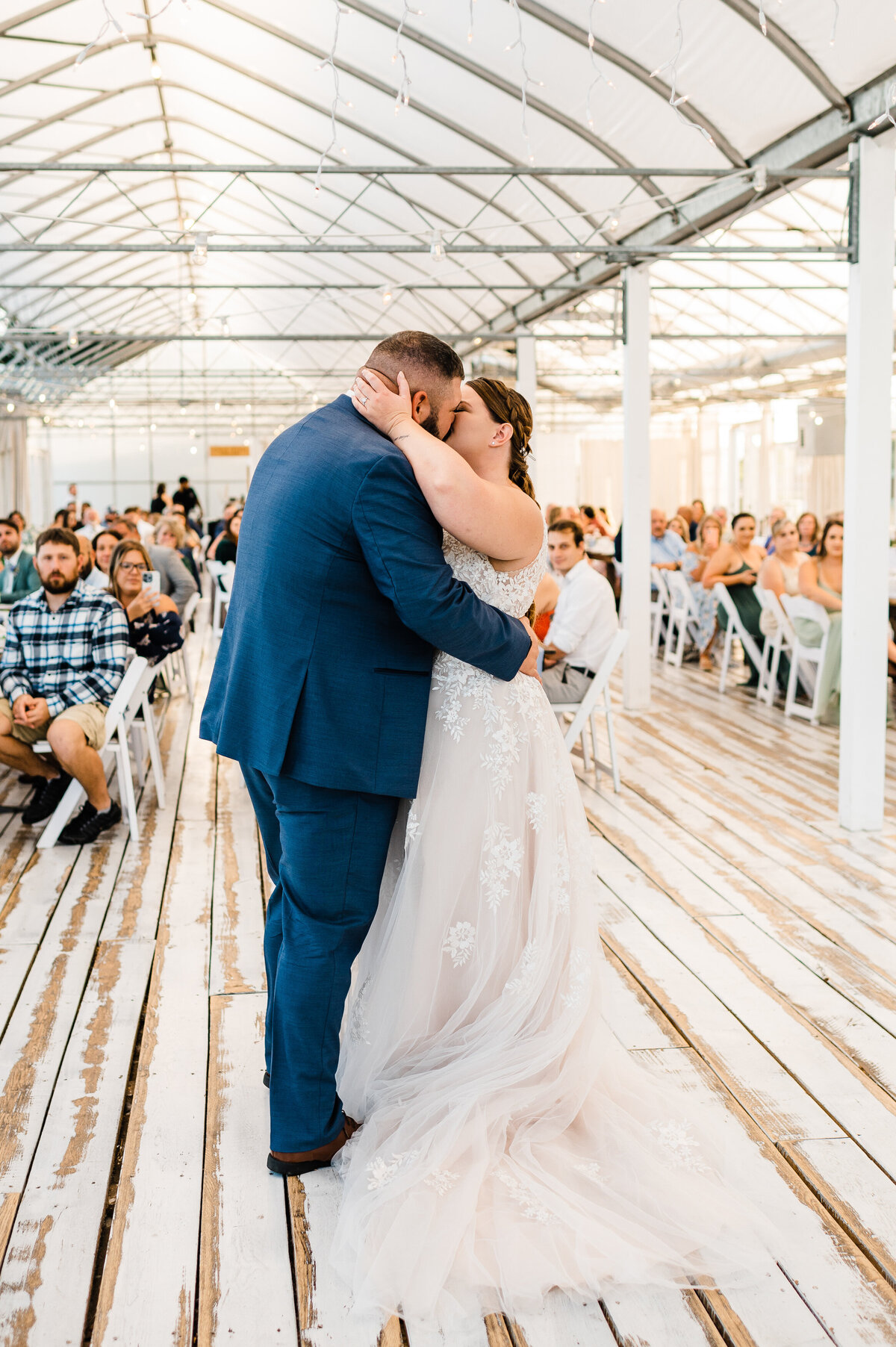 bride and groom kissing one another in the middle of the dance floor during their first dance at greenhouse wedding venue