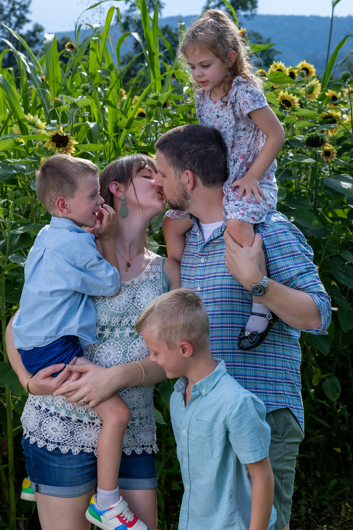 Parents with their two children smiling together in a sunflower field, captured by Capture Joy Photography, Northern Virginia family photographer.