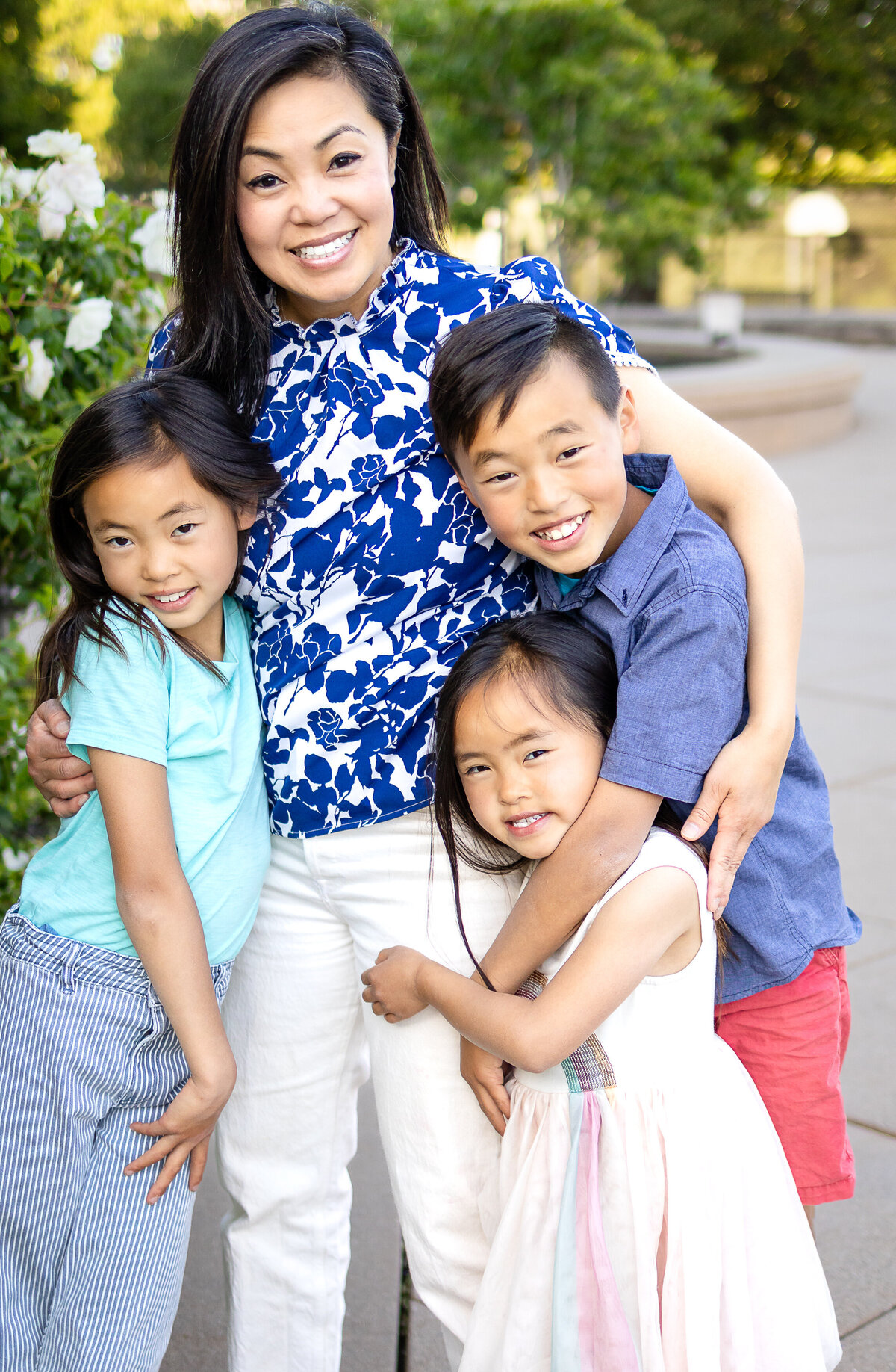 Mom sharing a warm hug with her three children during a playful outdoor session – lifestyle family photography by Ellobelle Photography, San Francisco Peninsula kohl mansion Burlingame