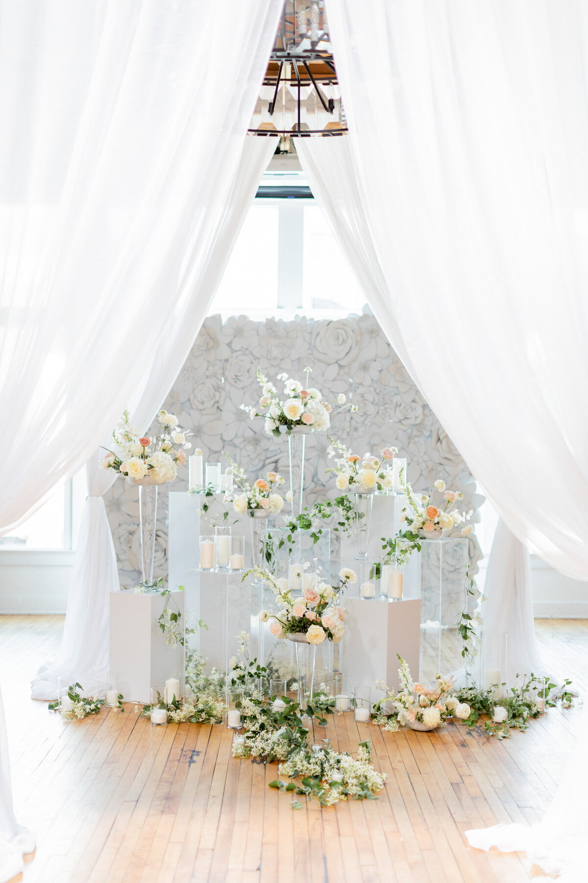 A wedding ceremony with white drapes and flowers.