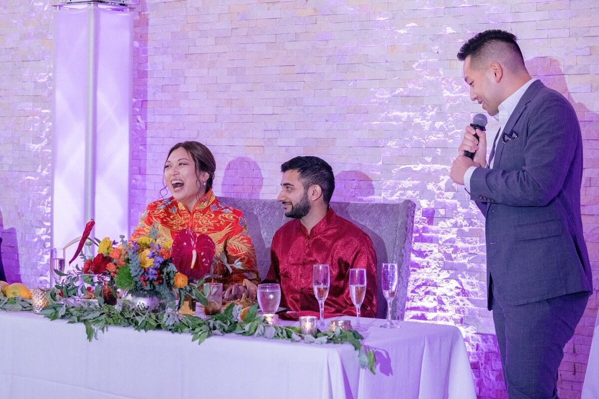 Brother of the bride makes bride laugh during the Chinese Indian fusion wedding.  