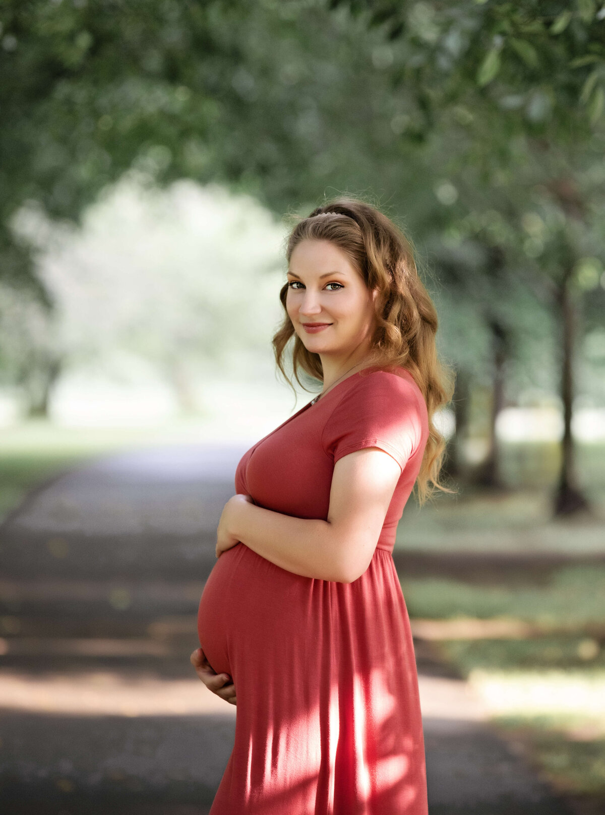 Beautiful maternity portrait of a young woman in dark pink dress at Frontier Park in Erie Pa