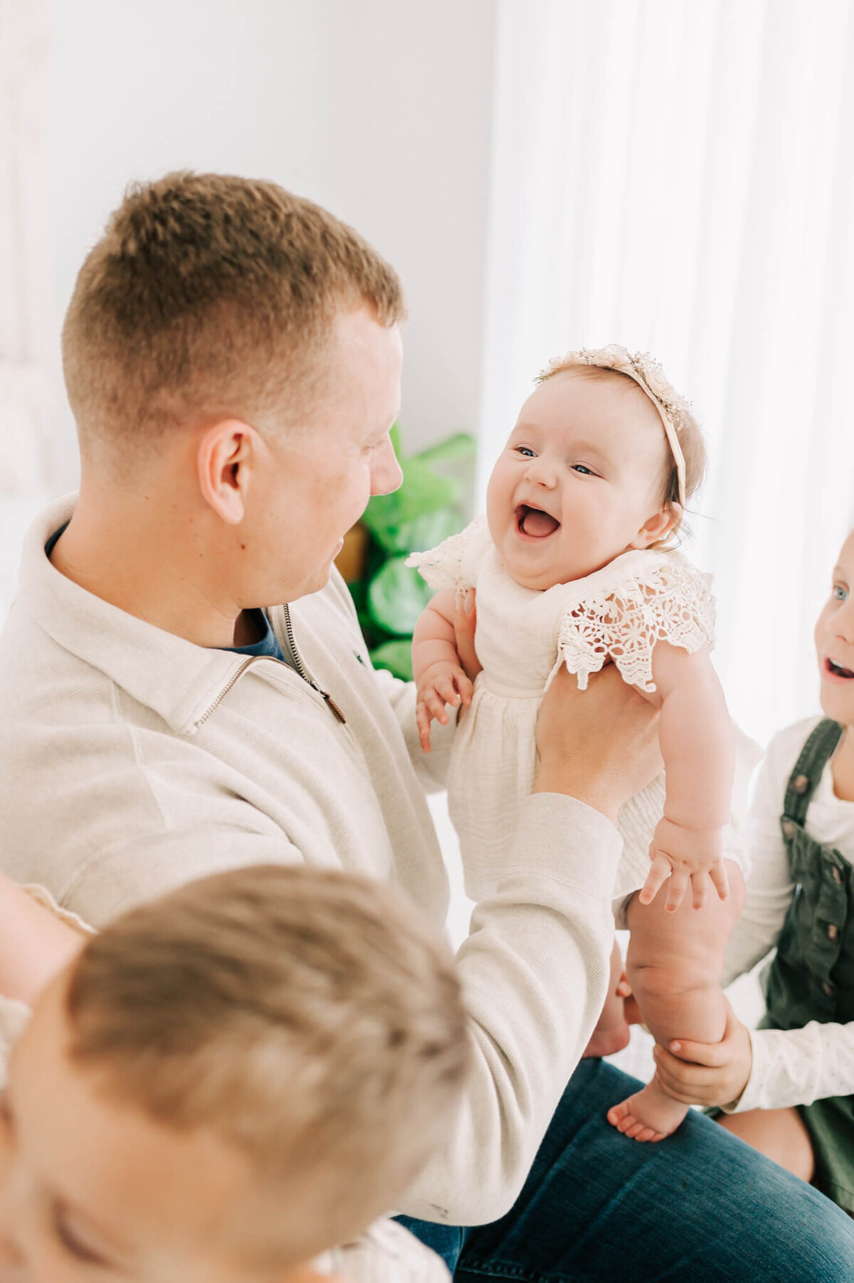 dad holding smiling baby in family photography studio in Springfield MO